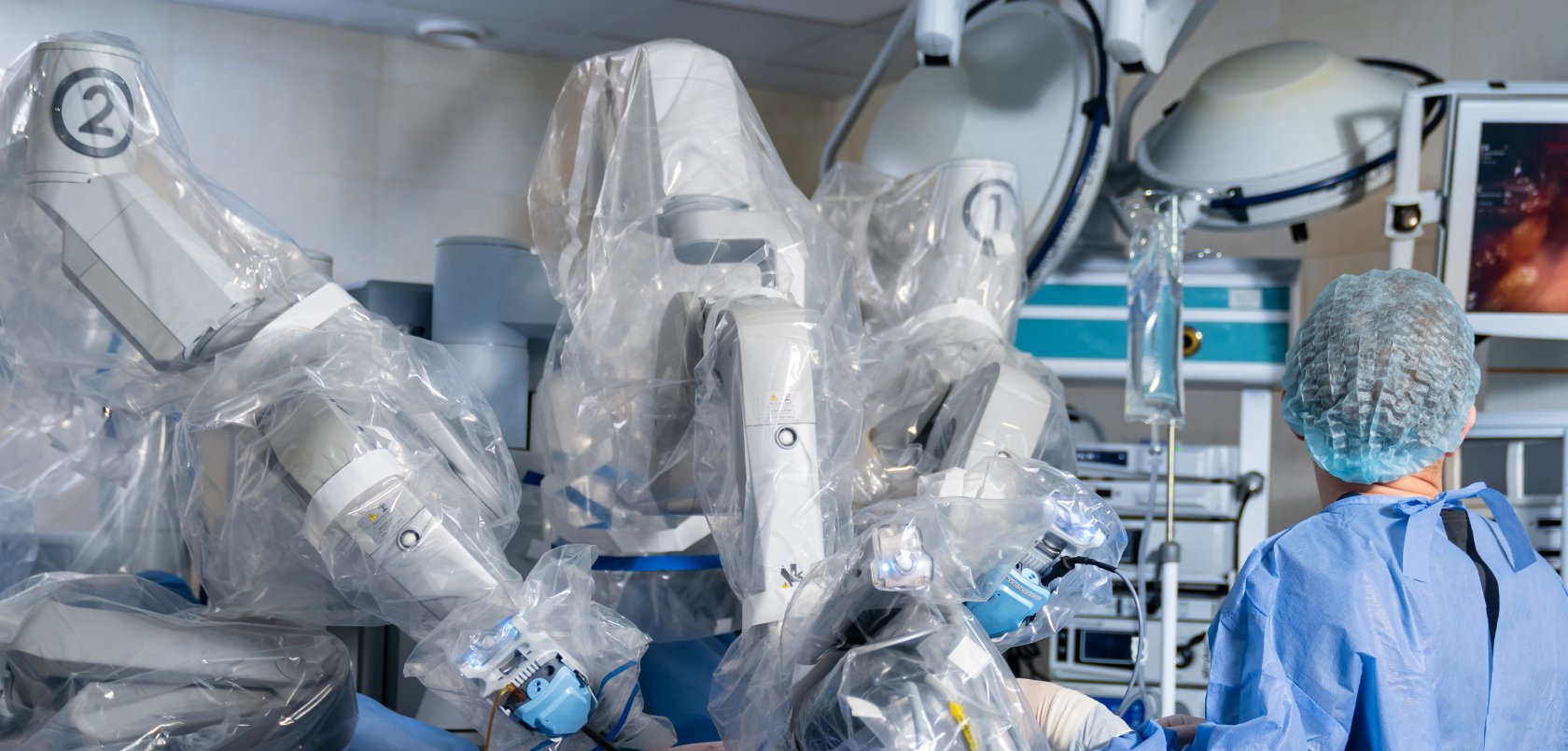 Surgeon using robotic-assisted surgical device and looking at a surgical navigation screen.