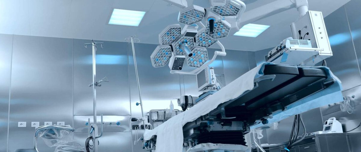An empty surgical suite, showing a surgical bed, lights, and displays.