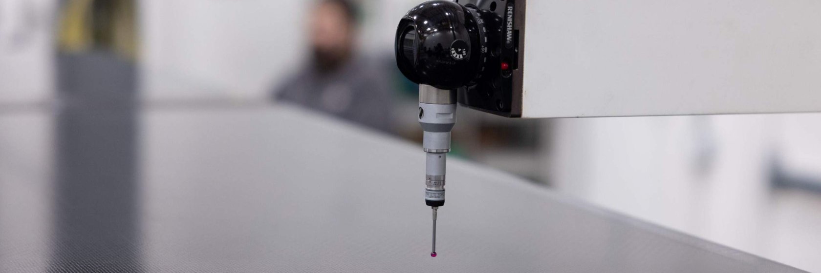 Close-up of a precision industrial measuring probe inspecting a flat surface in a manufacturing or quality control environment
